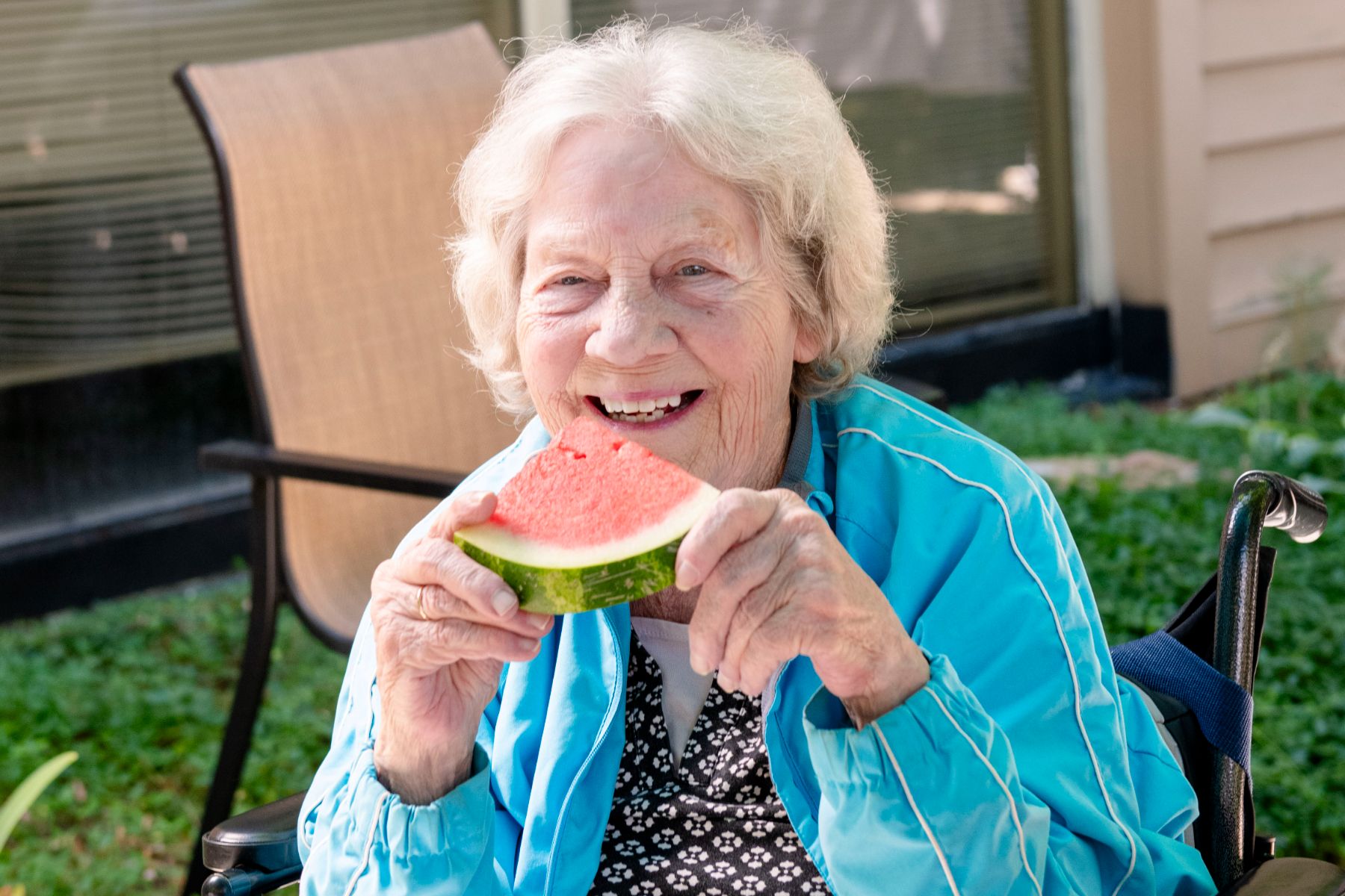 Someren Glen Senior Living Community in Centennial, CO - older woman smiling and holding watermelon slice landscape